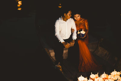 Man and woman sitting on display at night