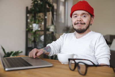 Smiling man in wheelchair with laptop on table