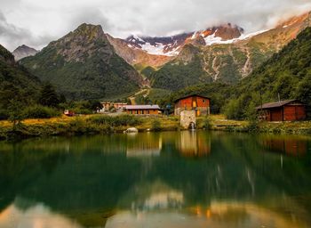 Scenic view of lake by buildings and mountains against sky