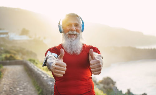 Portrait of bearded man listening music showing thumbs up