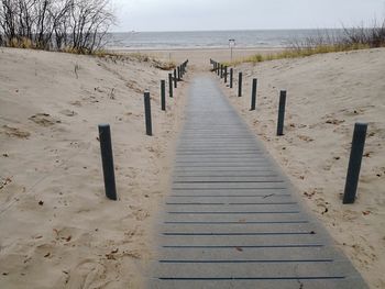 Wooden posts on beach against sky