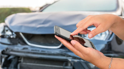 Midsection of man using mobile phone in car