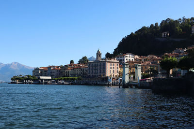 Buildings by mountain against clear blue sky