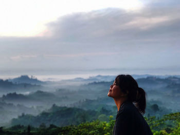 Side view of woman looking away against sky