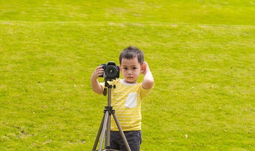 Cute boy photographing while standing at park