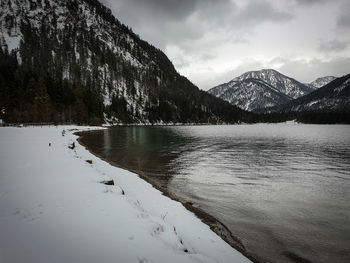 Scenic view of lake by snowcapped mountains against sky