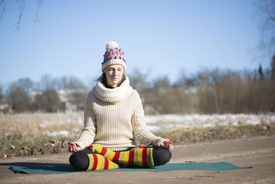 Beautiful calm lady practicing yoga on the rural road during winter or early spring
