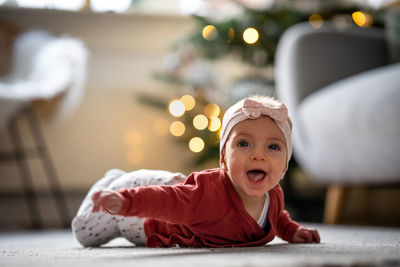 Portrait of cute baby girl with mouth open lying on carpet