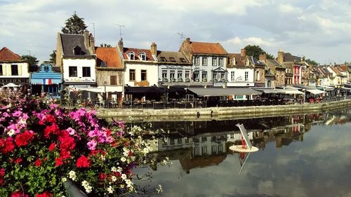 Canal amidst houses and buildings against sky