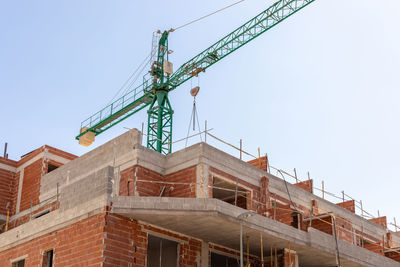 Vivid capture of construction site showcasing building in progress with brickwork and crane 