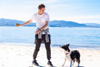 Young man playing with his dog on the beach