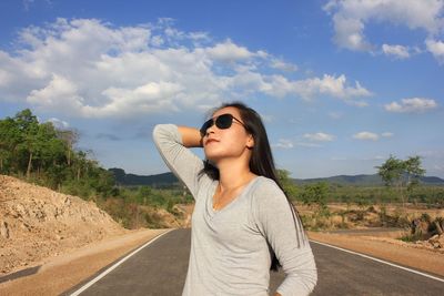 Young woman standing on road against sky