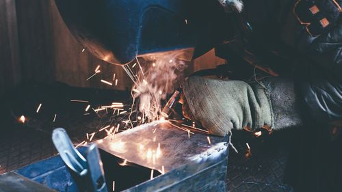The man conducts welding of metal by electric arc welding.