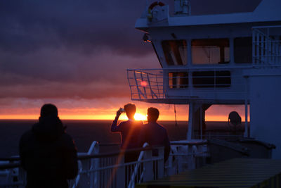 People take photos of sunset on a cruise ship