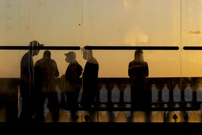 Rear view of people standing against window