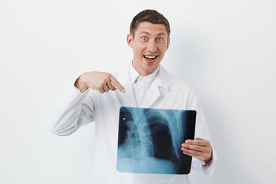 Portrait of smiling young man using mobile phone against white background