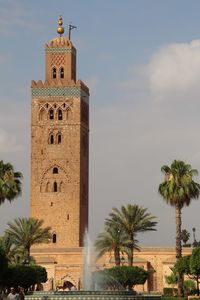 Clock tower by palm trees against sky