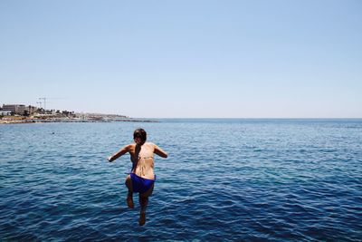Full length of man in sea against clear sky