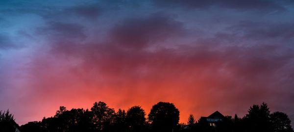 Low angle view of silhouette trees against dramatic sky