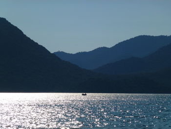 Scenic view of sea and mountains against clear sky