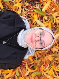 High angle portrait of woman wearing autumn leaves