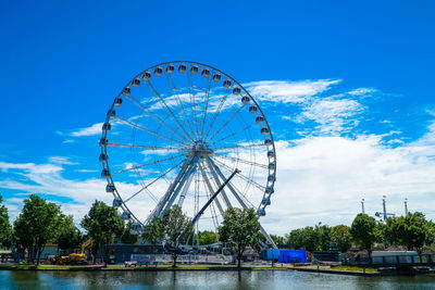 Ferris wheel by river against sky