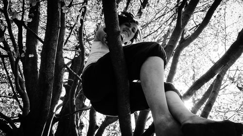 Low section of a young woman sitting on tree trunk in forest