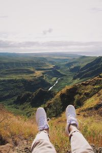 Low section of man on mountain against sky