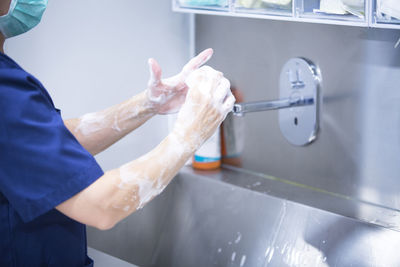 Midsection of doctor washing hands with soap