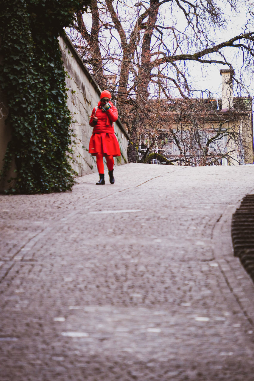 FULL LENGTH OF WOMAN WALKING ON FOOTPATH AMIDST BARE TREES