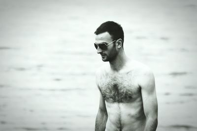 Young man looking away while standing on beach