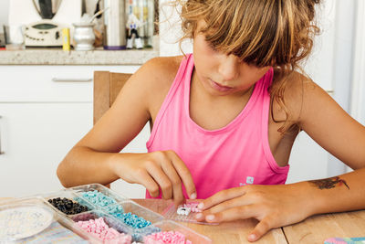 Midsection of woman with pink hair sitting on table at home