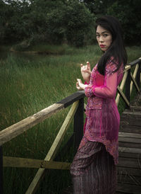 Young woman standing by pink umbrella against trees