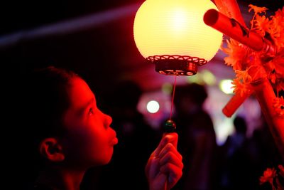 Close-up of boy looking away while holding illuminated lantern