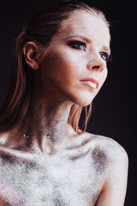 Close-up portrait of young woman against black background