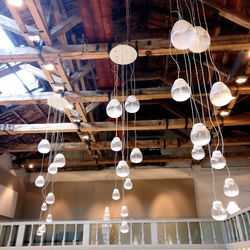 Low angle view of illuminated electric lamp hanging on ceiling