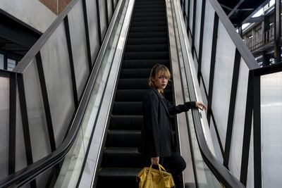 Woman standing on escalator