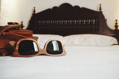 Sunglasses with shoulder bag on bed