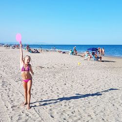 People at beach against clear blue sky