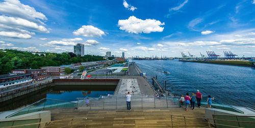 People on bridge over river against sky