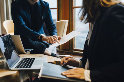 Midsection of male and female colleagues discussing over document in office