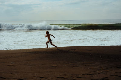 Full length of shirtless boy on beach