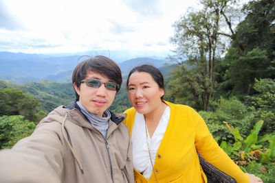 Portrait of a smiling young couple against trees