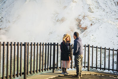 The woman is smiling in front of her boyfriend with an active volcano view.