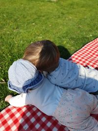 Rear view of siblings lying on picnic blanket during sunny day