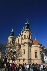 Group of people in front of building against clear blue sky