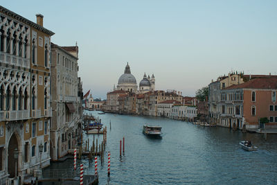 Boats in canal amidst buildings in city against clear sky venice 