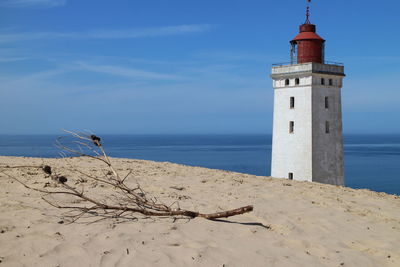 Sandy shore against old lighthouse