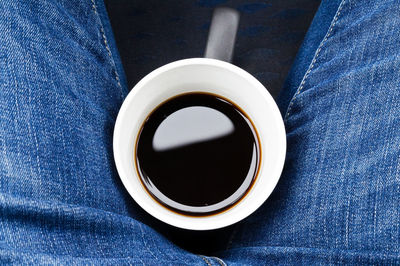 Directly above shot of black coffee between person lap