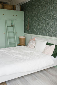 The interior of the bedroom is in a modern style. mint wardrobe and white bed with colorful pillows